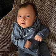 Lillian joined the competition — help win amazing prizes! baby, infant, blue_onesie, blanket, texture, cozy, cute, child, portrait, indoor, newborn, clothing, hands, face, head, eyes, expression, sitting, soft, comfort