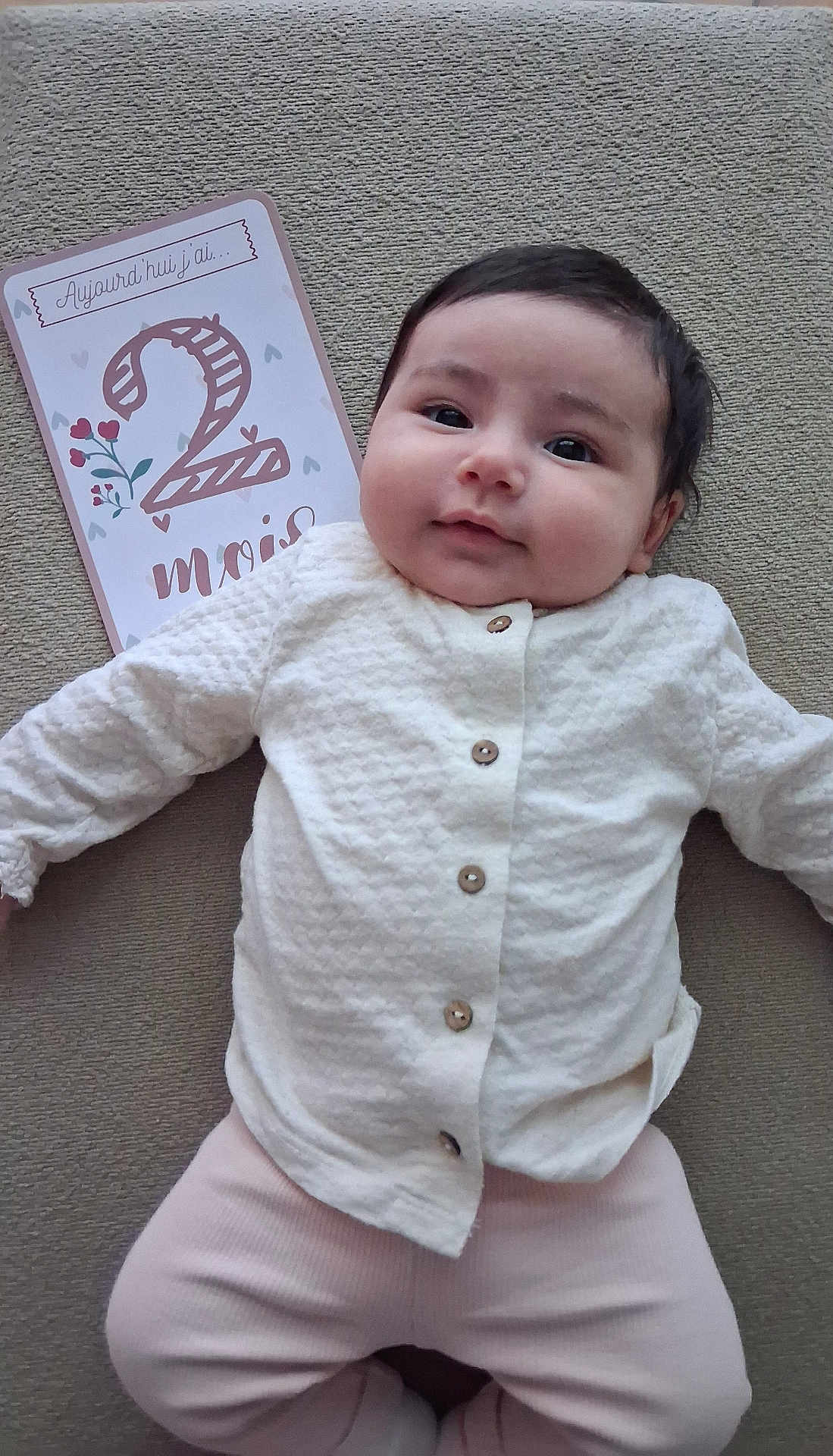 Lïa participe au concours pour gagner de l'argent avec cette photo : baby, infant, smile, milestone_card, clothing, white_shirt, pink_pants, lying_down, face, head, cute, child, two_months, milestone, soft_texture, portrait, young_child, indoors, person, baby_girl