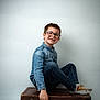 child, boy, glasses, denim_shirt, jeans, socks, sitting, vintage_suitcase, smile, portrait, indoor, casual, happy, young, fashion, studio, kid, person, isolated, background