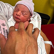 Adriel is registered to the contest to win money with this photo: newborn, baby, infant, hospital, blanket, hat, hand, person, sleeping, wrapped, arm, skin, hospital_id, closeup, indoors, resting, peaceful, human, portrait, care