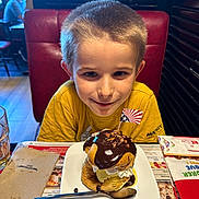 Sacha participe au concours pour gagner de l'argent avec cette photo : child, boy, dessert, chocolate, ice_cream, plate, spoon, table, restaurant, booth, napkin, glass, yellow_shirt, happy, food, indoor, flag, sweet, smile, person