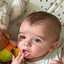 baby, infant, child, face, hand, toy, plush_toy, eyes, fingers, mouth, clothing, patterned_background, closeup, cute, indoor, soft_toys, expression, curious, skin, head