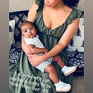 Isaiah joined the competition — help win amazing prizes! woman, baby, child, green_dress, white_shoes, striped_shorts, bench, pillow, indoor, floor_tiles, curly_hair, holding, portrait, family, love, casual_clothing, text_overlay, smiling, affection, seated