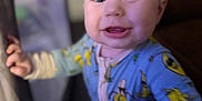 Waylon joined the competition — help win amazing prizes! baby, child, onesie, blue_clothing, banana_pattern, playpen, indoor, face, smile, happy, young_child, closeup, person, human, cute, expression, hand, head, infant, portrait
