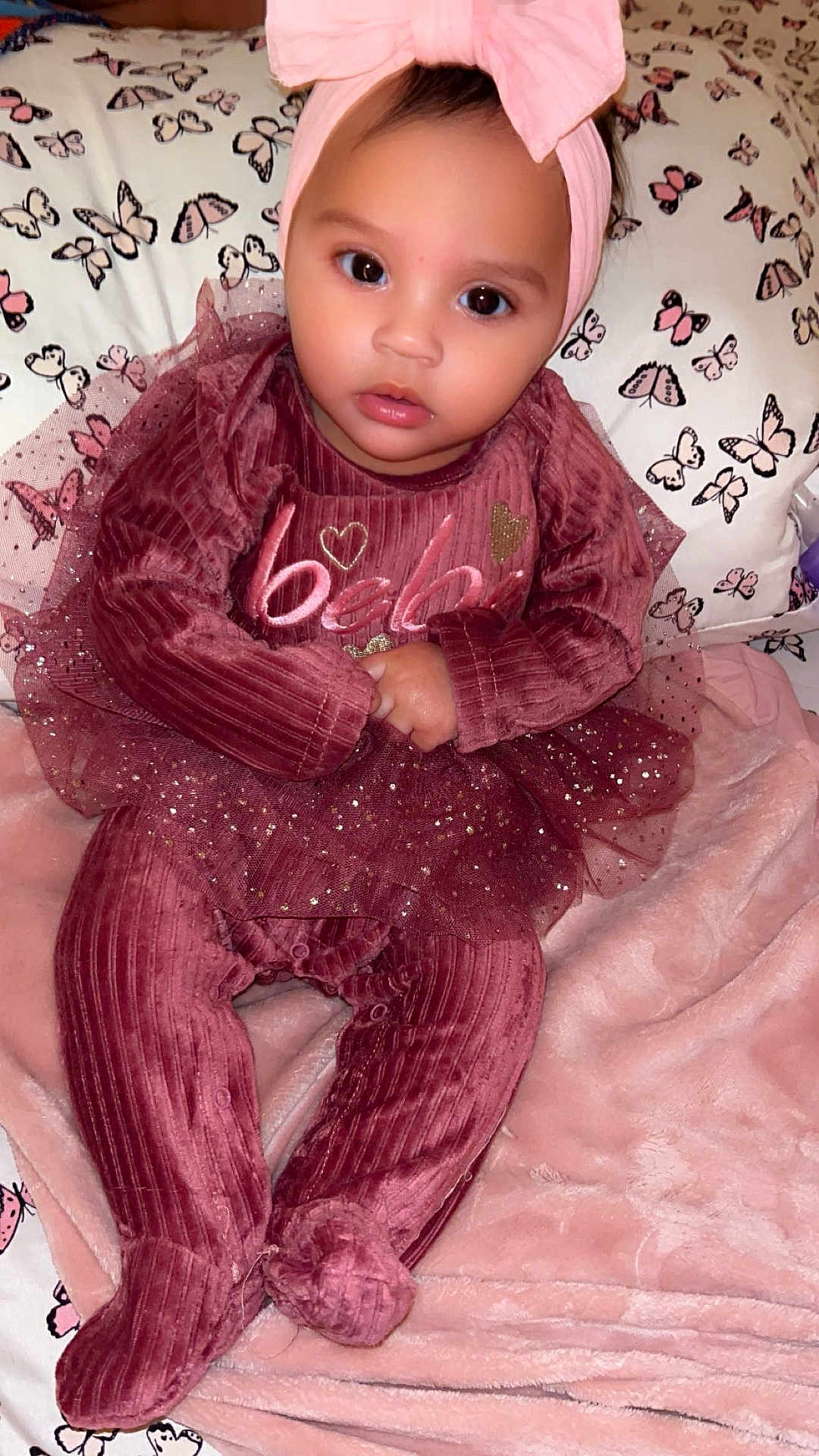 Dream joined the competition — help win amazing prizes! baby, infant, child, velvet_clothing, headband, pink, maroon, sparkles, blanket, pillow, butterfly_pattern, soft_texture, indoors, portrait, cute, sitting, toddler, face, eyes, hands