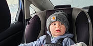 Colton joined the competition — help win amazing prizes! toddler, car_seat, blanket, beanie, child, car_interior, rain, window, clothing, seatbelt, hoodie, face, person, safety, indoor, transportation, cute, young_child, cold_weather, travel