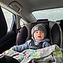 toddler, car_seat, blanket, beanie, child, car_interior, rain, window, clothing, seatbelt, hoodie, face, person, safety, indoor, transportation, cute, young_child, cold_weather, travel