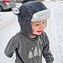 Colton is registered to the contest to win money with this photo: child, toddler, hat, winter_clothing, sweatshirt, smiling, snow, outdoor, cold_weather, street, blurred_background, happy, cute, playful, daylight, casual, person, headwear, winter, fun