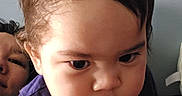 Nicholas is registered to the contest to win money with this photo: toddler, child, baby, portrait, face, person, serious, indoors, close_up, dark_shirt, black_hair, brown_hair, eyes, mouth, sitting, adult, background, warm_lighting, photography, family