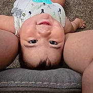 Nicholas is registered to the contest to win money with this photo: baby, infant, child, face, eyes, smiling, happy, lying_down, upside_down, portrait, indoor, carpet, cushion, adult, arms, diaper, teether, toy, closeup, photography