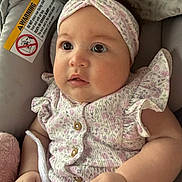 Brianna joined the competition — help win amazing prizes! baby, infant, child, face, headband, clothing, floral_pattern, hands, blanket, soft_texture, warning_label, car_seat, cute, portrait, indoors, skin, expression, sitting, closeup, person