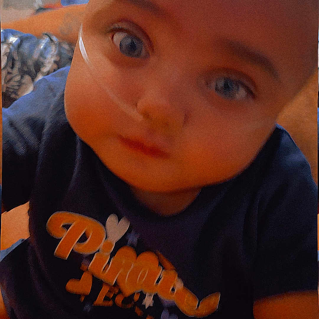 Kinzlee is registered to the contest to win money with this photo: baby, child, indoor, closeup, face, blue_shirt, toy, curious, young_child, sitting, infant, cute, looking_at_camera, soft_lighting, blurred_background, warm_colors, head, expression, person, portrait