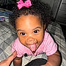 toddler, child, baby, pink_bow, curly_hair, tongue_out, crawling, hand, blanket, indoor, bedroom, person, smiling, cute, playful, closeup, face, happy, clothing, infant