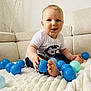 Maëlo participe au concours pour gagner de l'argent avec cette photo : baby, child, blue_balls, white_tshirt, couch, indoor, smiling, happy, cute, plush_blanket, sitting, infant, toy, playtime, portrait, face, feet, home, light, decor