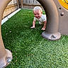 Emerson is registered to the contest to win money with this photo: toddler, child, playground, crawling, artificial_grass, smiling, outdoor, fence, play_structure, happy, baby, grass, toy, person, young_child, casual_clothing, daylight, adventure, cute, playtime