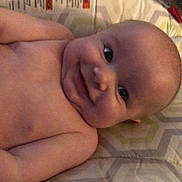 Emerson is registered to the contest to win money with this photo: baby, smile, face, infant, cushion, pattern, skin, head, eyes, lying_down, indoors, child, person, happy, closeup, young, cute, human, cheeks, expression