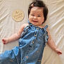 baby, smiling, denim, clothing, infant, hair_clip, plaque, milestone, bed, soft, cute, portrait, child, happy, lying_down, fabric, button, cherry_pattern, skin, indoor