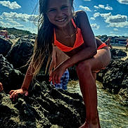 Lélina participe au concours pour gagner de l'argent avec cette photo : child, girl, bikini, rocks, water, beach, sunny, smiling, outdoor, sky, clouds, summer, vacation, playful, nature, barefoot, happy, portrait, sunlight, holiday