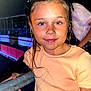 child, girl, braids, smile, peach_shirt, railing, night, outdoor, portrait, face, person, young, happy, event, casual_clothing, holding, flash, skin, hair, background