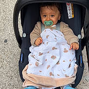Noé a rejoint le concours — aidez-le/la à gagner de superbes lots ! baby, infant, car_seat, pacifier, blanket, beige_clothing, blue_sock, outdoor, sidewalk, shopping_bag, holiday_theme, person, child, cute, young, seated, face, head, expression, bundle