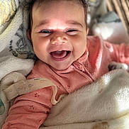 Taliah joined the competition — help win amazing prizes! baby, smiling, happy, blanket, pink_clothing, infant, face, cute, portrait, cozy, child, indoors, closeup, expression, warm, soft, relaxed, joy, sleepwear, adorable