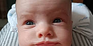 Clementine is registered to the contest to win money with this photo: baby, face, expression, close_up, skin, eyes, chubby, infant, portrait, cute, child, young, head, indoors, blanket, striped, human, resting, skin_texture, newborn