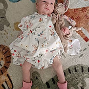 Clementine is registered to the contest to win money with this photo: baby, infant, dress, pink_socks, toy, stuffed_animal, bunny, carpet, animal_pattern, lying_down, child, cute, soft_toy, floor, indoors, person, baby_clothing, playtime, smile, comfort