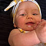 baby, child, headband, yellow, white, flower_pattern, smiling, face, arm, skin, closeup, portrait, infant, happy, cute, lying_down, background, soft_light, clothing, baby_girl
