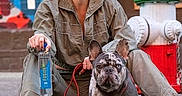 Smokey is registered to the contest to win money with this photo: woman, dog, french_bulldog, leash, street, fire_hydrant, casual_clothing, sneakers, smiling, urban, sidewalk, hydrant, colorful_background, pet, happy, outdoor, person, animal, daylight, portrait