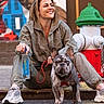 woman, dog, french_bulldog, leash, street, fire_hydrant, casual_clothing, sneakers, smiling, urban, sidewalk, hydrant, colorful_background, pet, happy, outdoor, person, animal, daylight, portrait