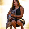 woman, dog, french_bulldog, pet, outdoor, sunlight, golden_hour, black_clothing, squatting, affection, animal, canine, young_adult, casual, footwear, pink_slippers, tattoo, bracelet, leash, nature