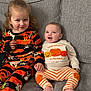Isaac joined the competition — help win amazing prizes! child, baby, couch, gray_couch, pumpkin_outfit, striped_pants, happy, smiling, sitting, plush_toy, home_interior, cute, infant, toddler, orange, fall_theme, cozy, clothing, siblings, portrait