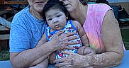 Caspian is registered to the contest to win money with this photo: baby, child, elderly_woman, glasses, outdoor, table, holding, family, casual_clothing, portrait, skin, arm, face, person, sitting, love, affection, relaxed, multigenerational, expression
