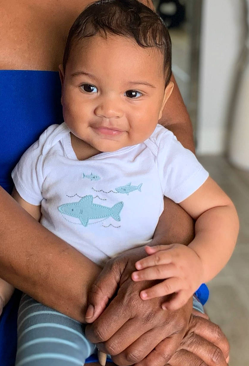 Jai is registered to the contest to win money with this photo: arm, baby_toddler_clothing, cheek, elbow, eye, face, finger, flash_photography, gesture, hand, happy, iris, joint, neck, person, product, shoulder, skin, sleeve, smile