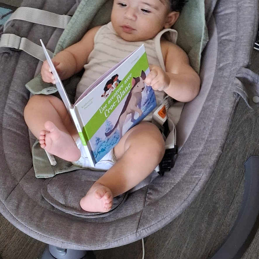 Daniel participe au concours pour gagner de l'argent avec cette photo : baby, baby_rocker, book, child, clothing, curly_hair, device, engaged, expression, floor, foot, hand, indoor, infant, modern, person, reading, relaxing, seat, technology