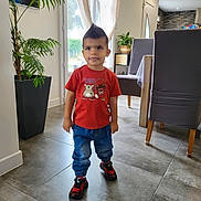 Luca a rejoint le concours — aidez-le/la à gagner de superbes lots ! blue_pants, casual_clothing, child, curtains, dining_chair, floor_tiles, hairstyle, indoor, living_room, modern_interior, person, plant, playful, red_tshirt, sneakers, standing, table, toddler, tongue_out, window
