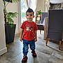 blue_pants, casual_clothing, child, curtains, dining_chair, floor_tiles, hairstyle, indoor, living_room, modern_interior, person, plant, playful, red_tshirt, sneakers, standing, table, toddler, tongue_out, window