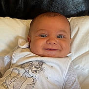 Loan a rejoint le concours — aidez-le/la à gagner de superbes lots ! baby, smiling, infant, pillow, white_clothing, cartoon, lion, face, eyes, happy, child, cute, indoor, portrait, closeup, newborn, person, apparel, fabric, couch