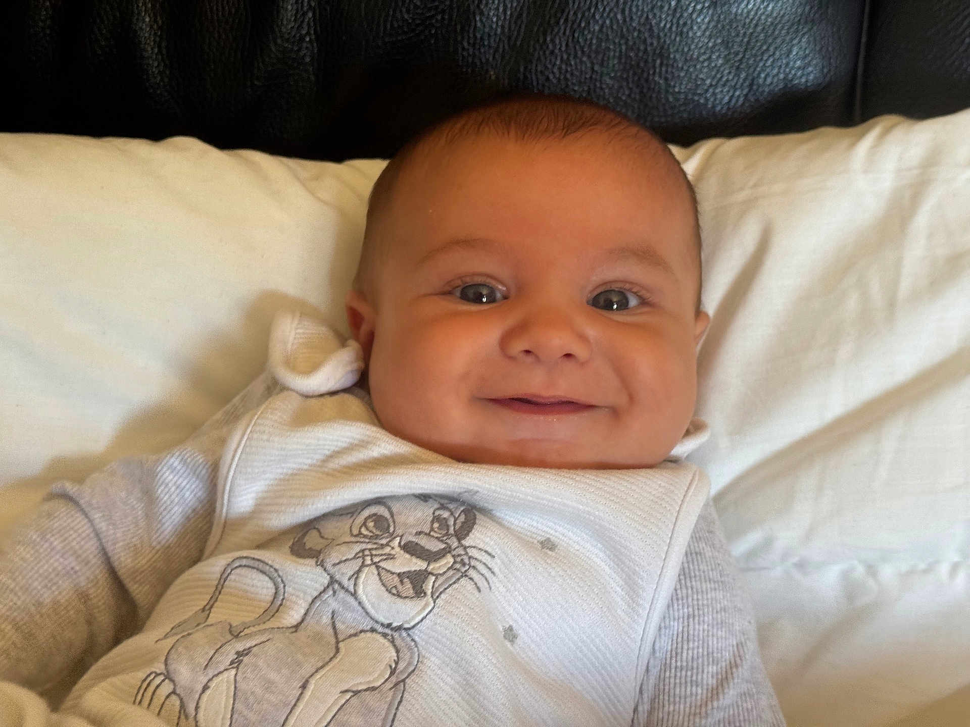 Loan a rejoint le concours — aidez-le/la à gagner de superbes lots ! baby, smiling, infant, pillow, white_clothing, cartoon, lion, face, eyes, happy, child, cute, indoor, portrait, closeup, newborn, person, apparel, fabric, couch