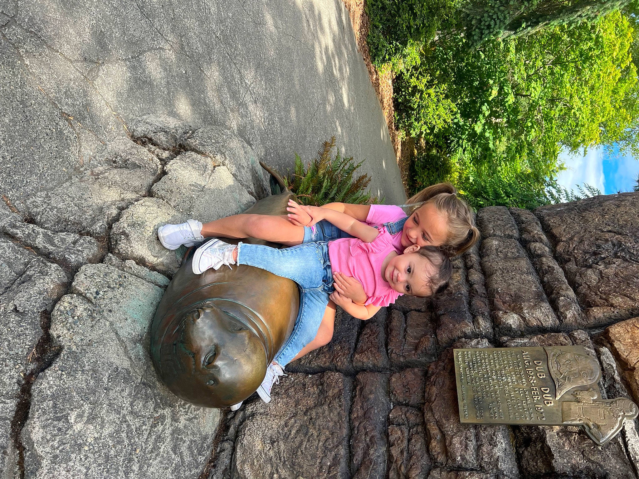 Braelynn joined the competition — help win amazing prizes! cobblestone, foot, fun, grass, happy, hat, human_leg, joy, landscape, leisure, people_in_nature, person, plant, recreation, rock, sandal, sidewalk, sitting, toddler, tree