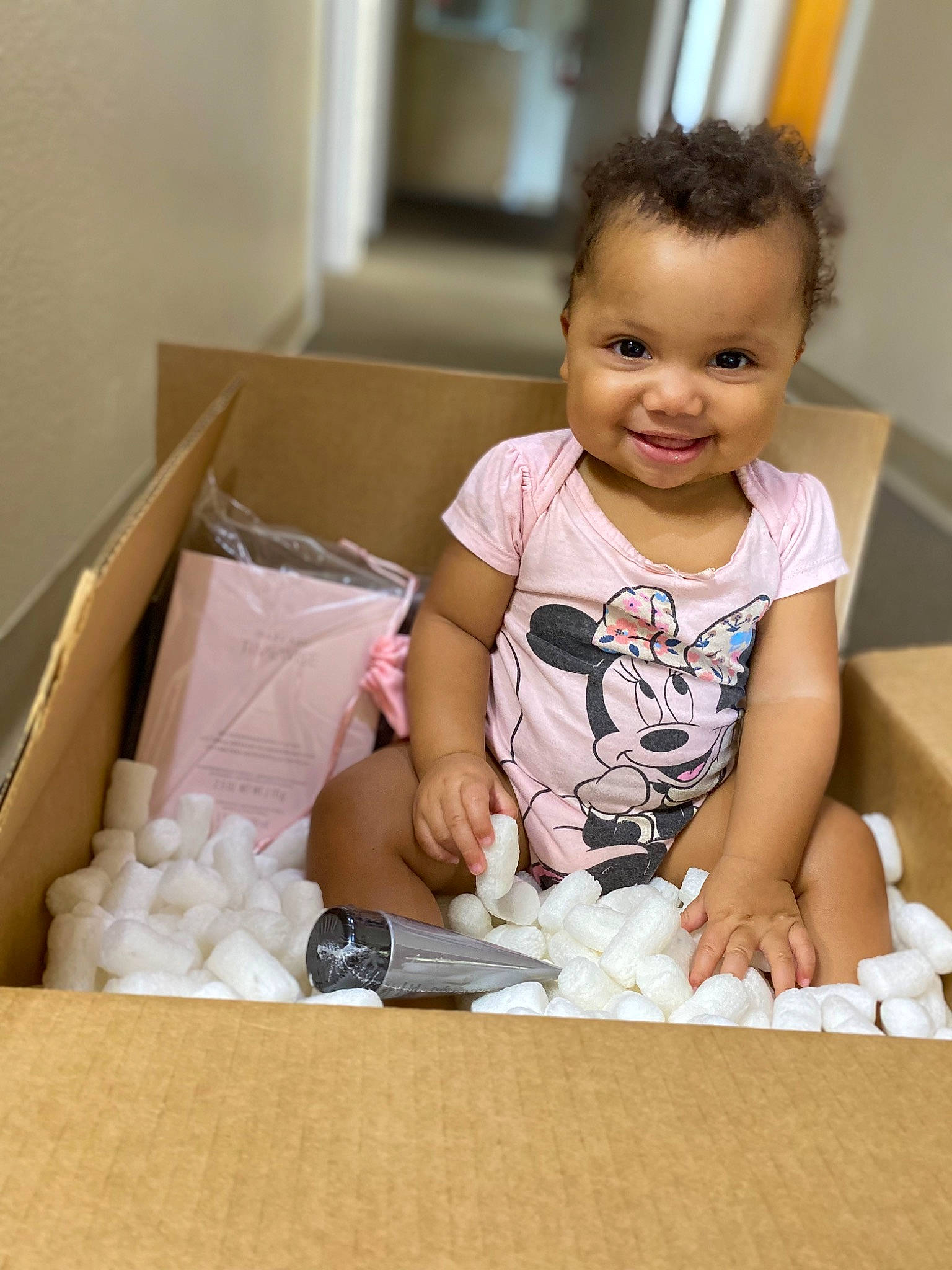 Serenity is registered to the contest to win money with this photo: baby, baby_toddler_clothing, box, carton, cheek, child, comfort, flooring, fun, happy, joy, packing_materials, person, pink, room, shipping_box, sitting, skin, sleeve, smile