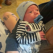 Bennett joined the competition — help win amazing prizes! baby, newborn, infant, pacifier, hat, striped_clothing, animal_print, tattoo, arm, person, indoor, carpet, dumbbells, basket, relaxing, cute, holding, portrait, child, casual