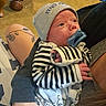 baby, newborn, infant, pacifier, hat, striped_clothing, animal_print, tattoo, arm, person, indoor, carpet, dumbbells, basket, relaxing, cute, holding, portrait, child, casual