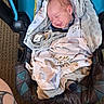 baby, infant, smile, blanket, car_seat, sleeping, face, head, child, cozy, fabric, pattern, comfort, indoor, person, newborn, wrapped, cute, peaceful, soft