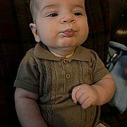 Jaxon joined the competition — help win amazing prizes! baby, child, pout, knitted_clothing, brown_outfit, couch, plaid, indoor, portrait, chubby_cheeks, cute, infant, sitting, hand, expression, young_child, face, skin, warm_lighting, cozy