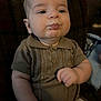 baby, child, pout, knitted_clothing, brown_outfit, couch, plaid, indoor, portrait, chubby_cheeks, cute, infant, sitting, hand, expression, young_child, face, skin, warm_lighting, cozy