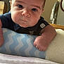 Jaxon is registered to the contest to win money with this photo: baby, infant, face, eyes, arm, hand, cushion, blue, pattern, indoor, bed, blanket, clothing, polo_shirt, cute, portrait, child, young, resting, soft
