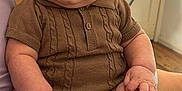 Jaxon joined the competition — help win amazing prizes! baby, child, infant, knitted_clothing, brown_clothing, sitting, indoor, person, hand, foot, face, serious_expression, lap, adult_arm, fan, furniture, home, skin, casual, portrait