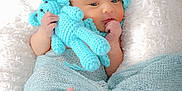 Elio participe au concours pour gagner de l'argent avec cette photo : newborn, baby, infant, knit_hat, blue, teddy_bear, blanket, wrapped, soft_texture, cozy, cute, sleepy, child, portrait, indoors, feet, hand, resting, white_background, warm