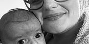 Elio participe au concours pour gagner de l'argent avec cette photo : affection, baby, black_and_white, child, close_up, clothing, cuddle, expression, face, fingernail, glasses, hair, hand, holding, indoor, person, portrait, smile, toy, woman